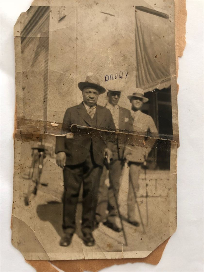 Before: a torn, stained old print of three men in hats outside a wooden house